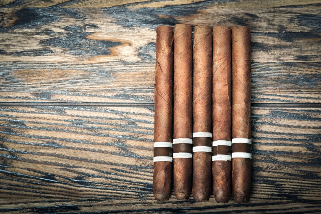 A group of cigars of various sizes on a wooden table.