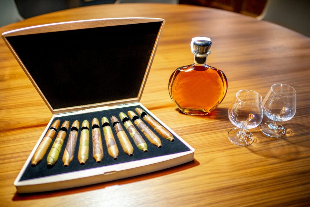 A bottle of bourbon and a set of glasses on a table, with cigar sizes explained.