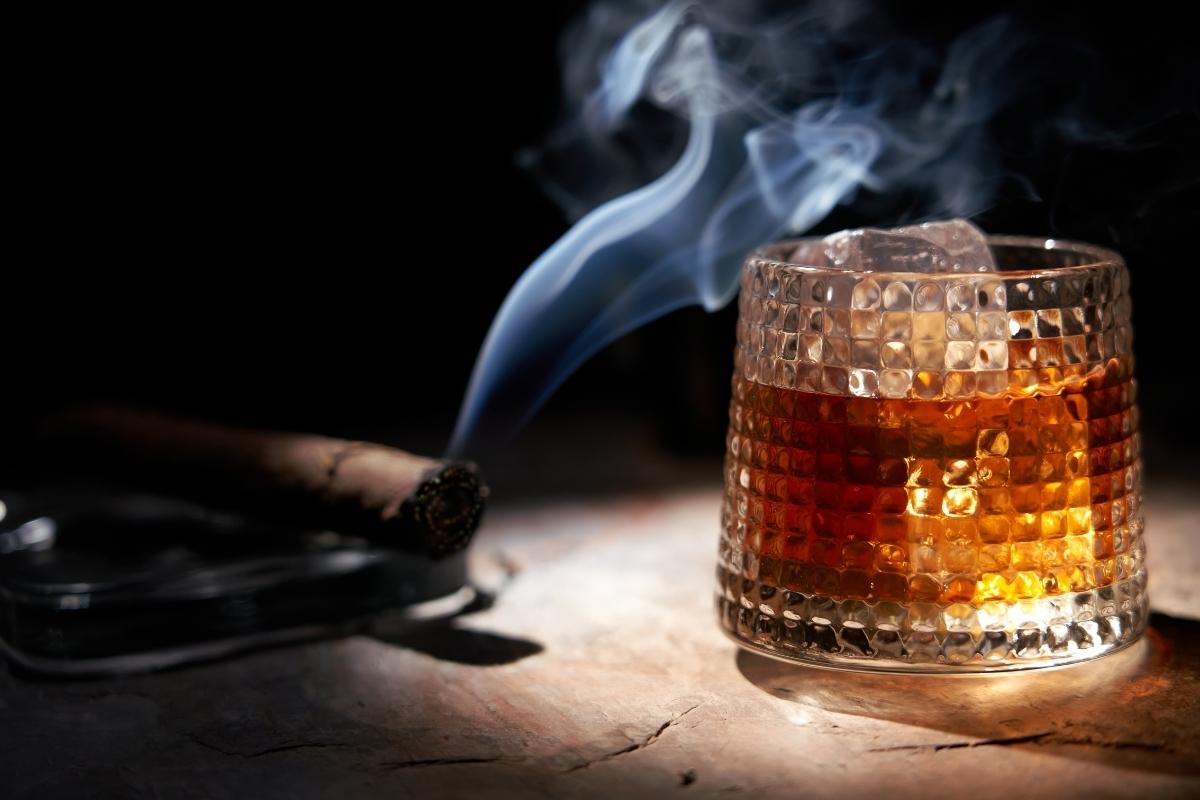 A glass of whiskey with smoke coming out of it, evoking a smoky atmosphere.