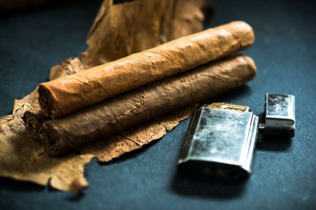 Cigar brands representative of different countries showcased alongside a lighter on a dark background.