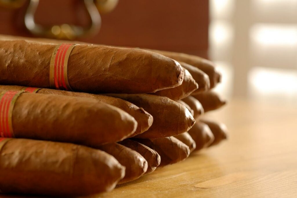 A collection of cigars from various countries displayed on a wooden table.