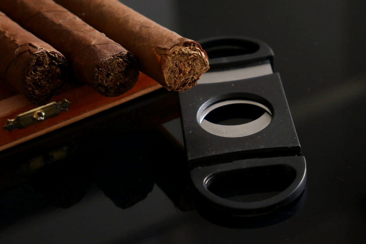 Various cigars of different sizes and a cigar cutter neatly arranged on a table.