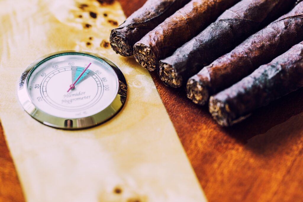 Cigars, hygrometer, and a thermometer on a wooden table.