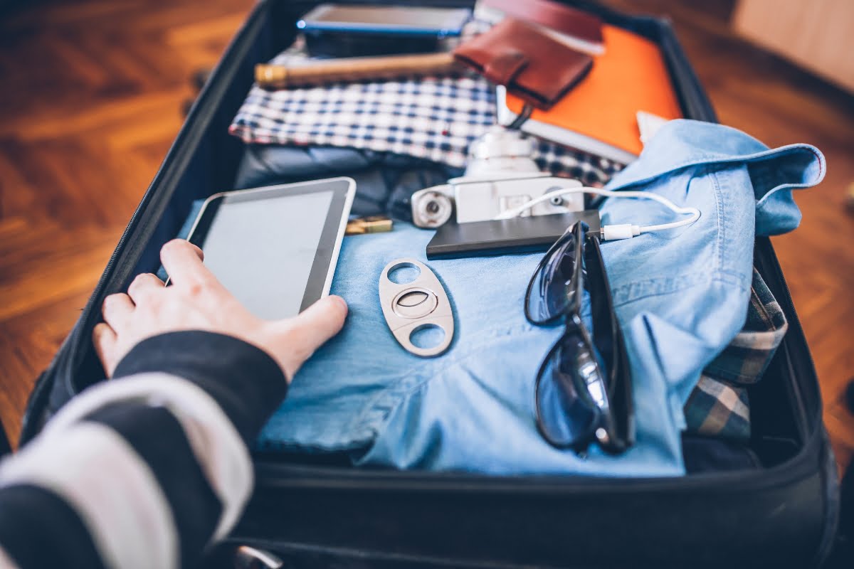 A person holding a tablet while traveling with cigars.