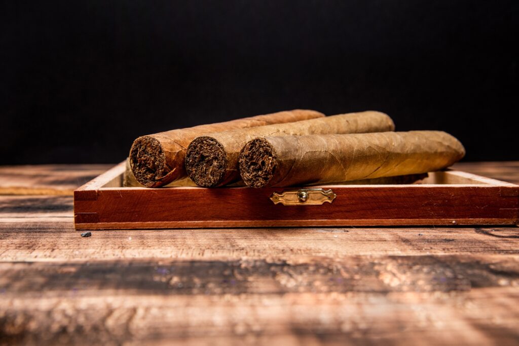 Travel with cigars in a wooden box on a dark background.