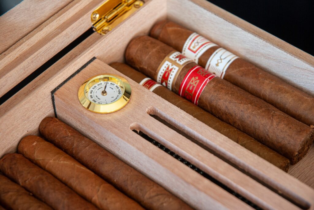 Cigars in a wooden box with an analog hygrometer.