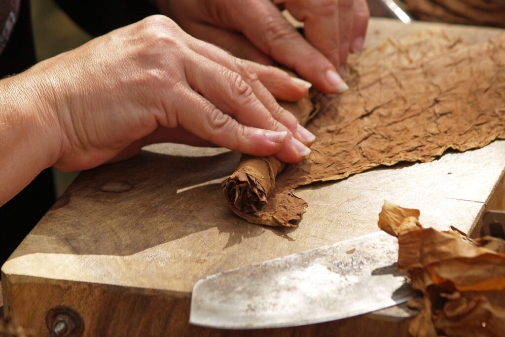 A person expertly slicing a piece of tobacco on a cutting board, revealing the secrets of an authentic smoke.