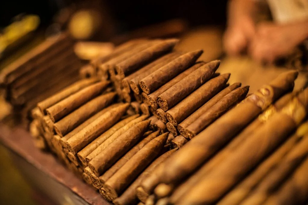 Authentic Puro Cigars are stacked on a table in front of a man, revealing the secrets of an enjoyable and authentic smoke.