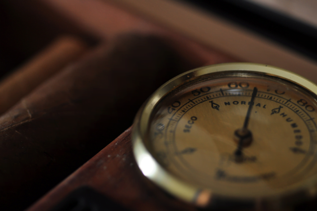 A hygrometer is placed on top of a cigar in order to monitor the humidity level.