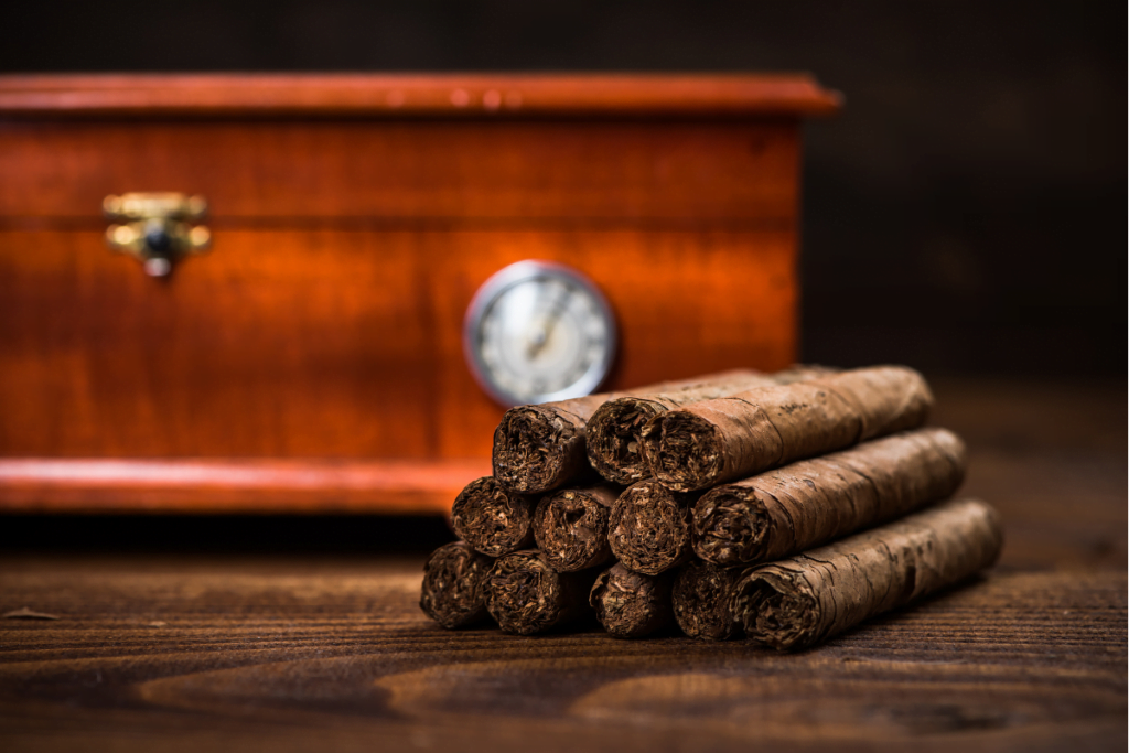 A few pieces of cigars with a humidor on a wooden table.