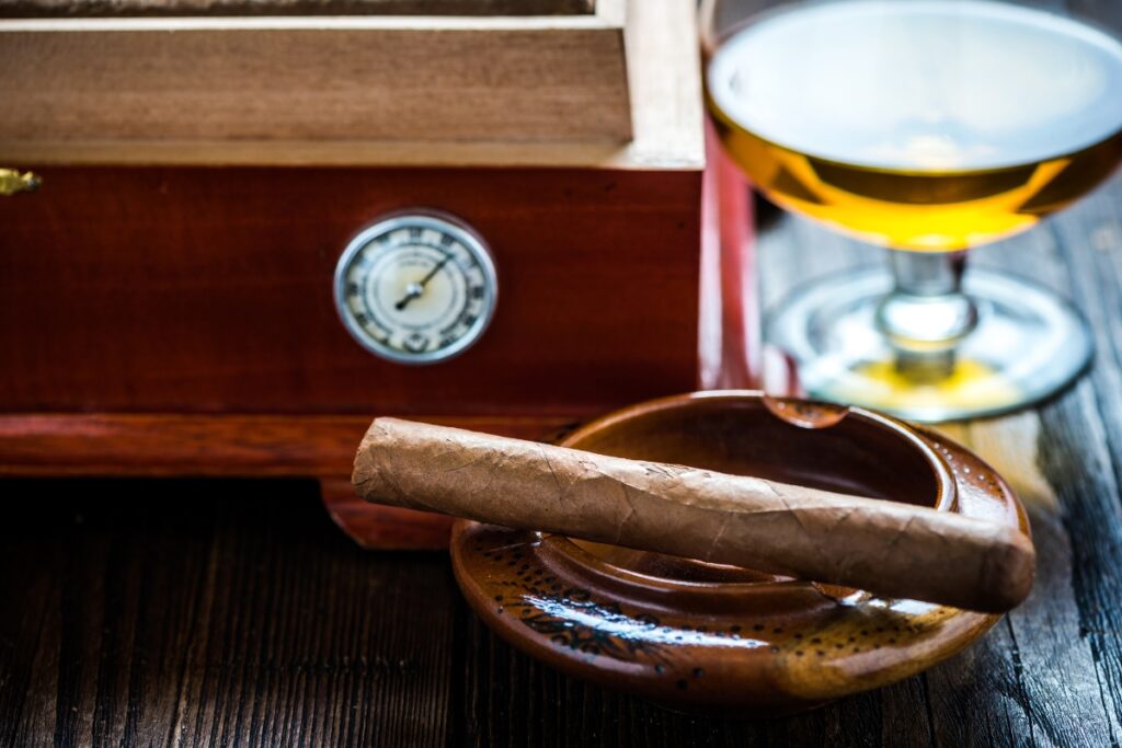 A glass of beer and a cigar on a wooden table while choosing a humidor.
