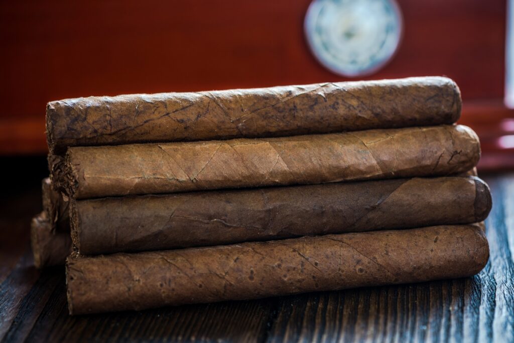 A stack of cigars neatly arranged on a wooden table, ready for humidor maintenance.