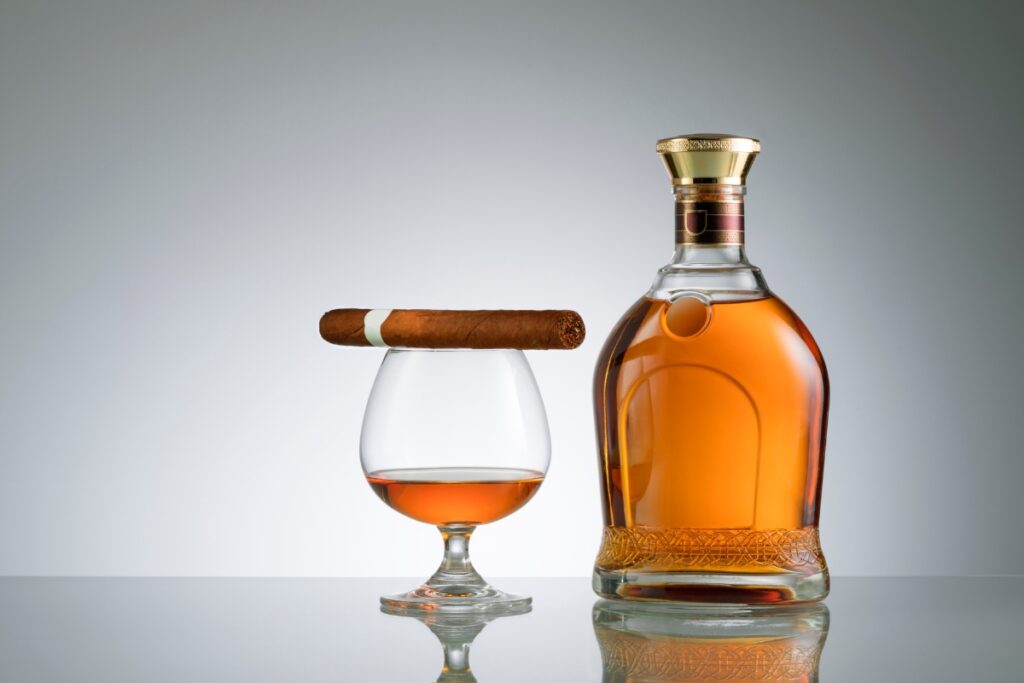 A bottle of rum and a glass of whiskey with cigar pairings.