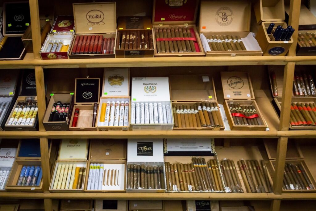 Shelves filled with assorted cigars in various boxes and packaging, neatly organized and displayed for sale in a store—a paradise for cigar collecting enthusiasts.