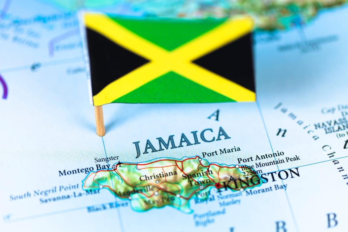 Jamaican flag on a map highlighting Jamaica, a prime travel destination for cigar lovers. Nearby locations include Montego Bay, Port Antonio, and Kingston.